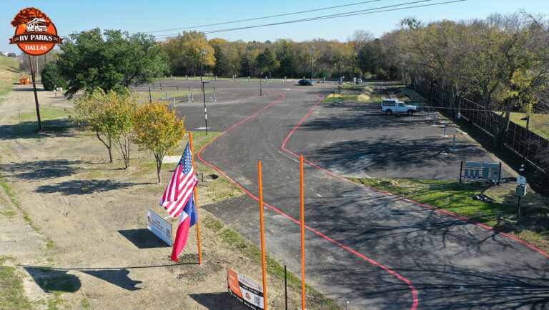 Entrance of Dallas Melissa RV Park with U.S. and Texas flags and a paved road leading to the sites